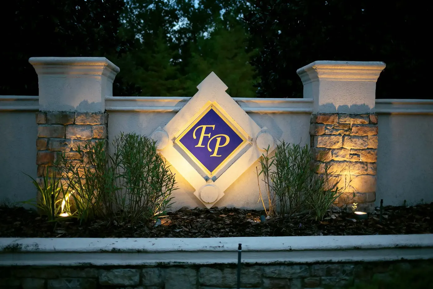 Neighborhood entrance monument with uplighting at dusk