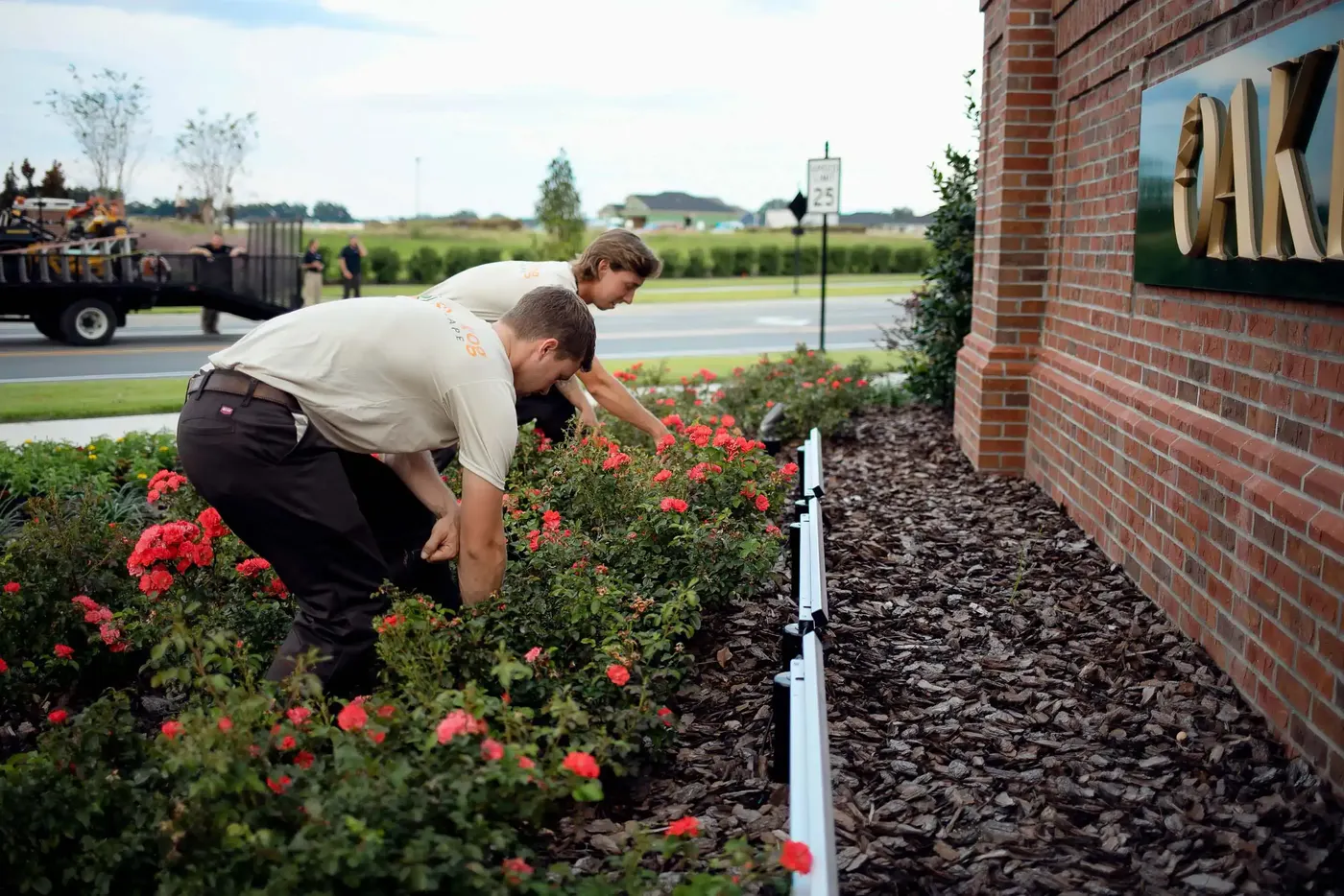 SkyFrog crew member tending roses at a brick neighborhood entrance