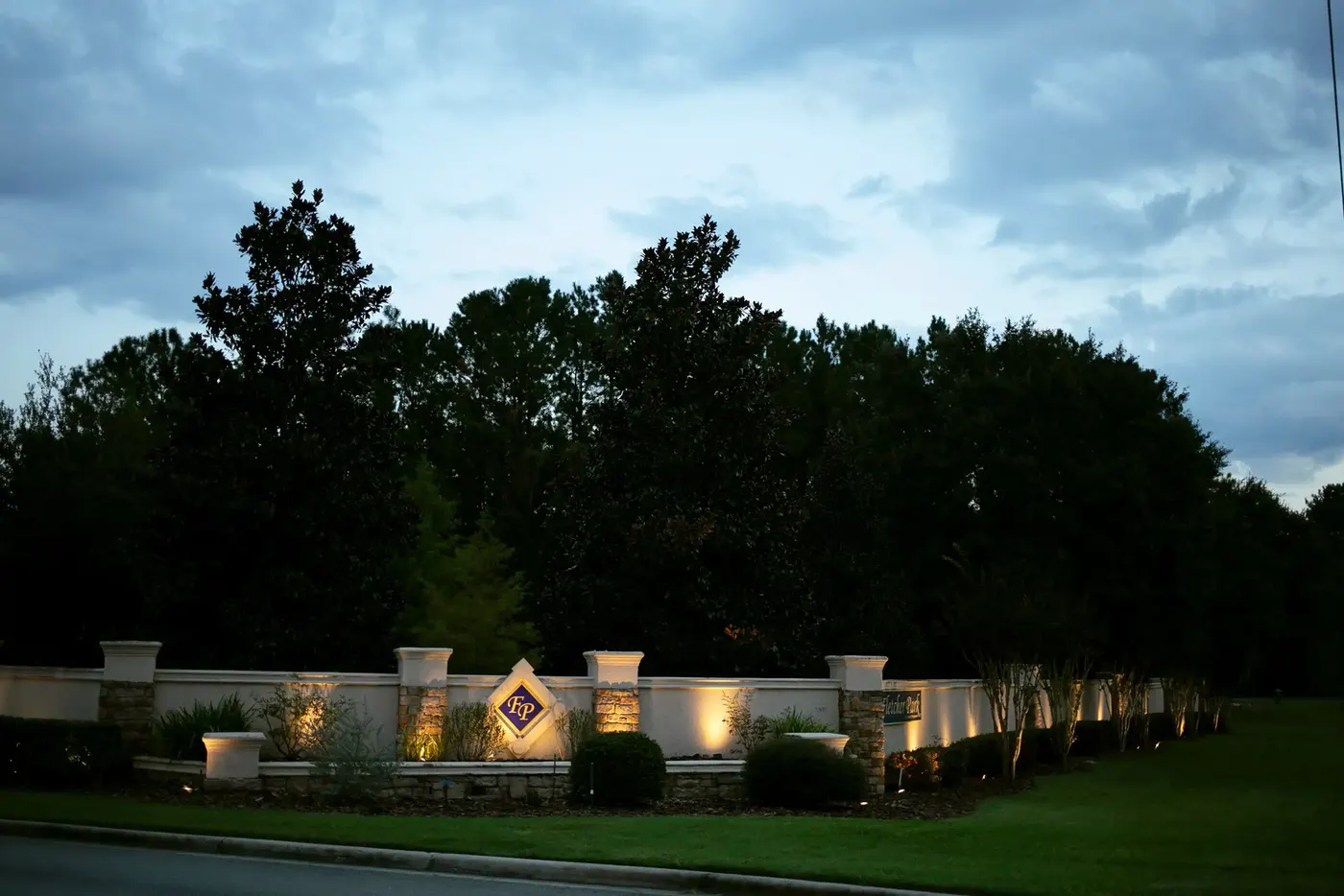 Long neighborhood entrance wall uplit at dusk