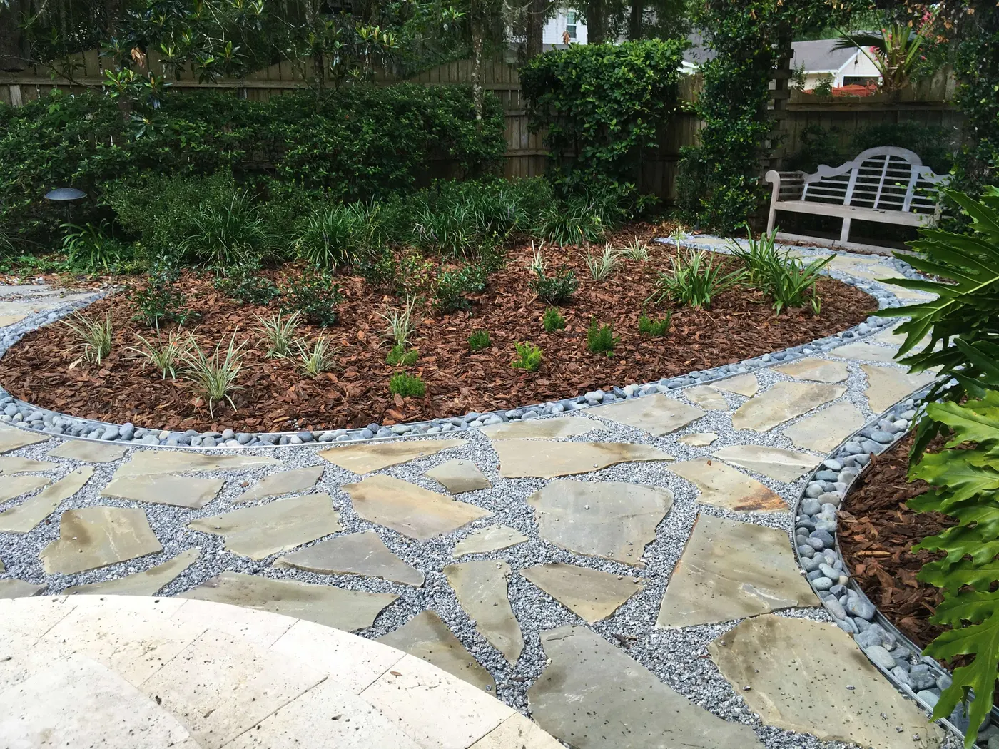 Flagstone circle patio with a bench beside a pool enclosure