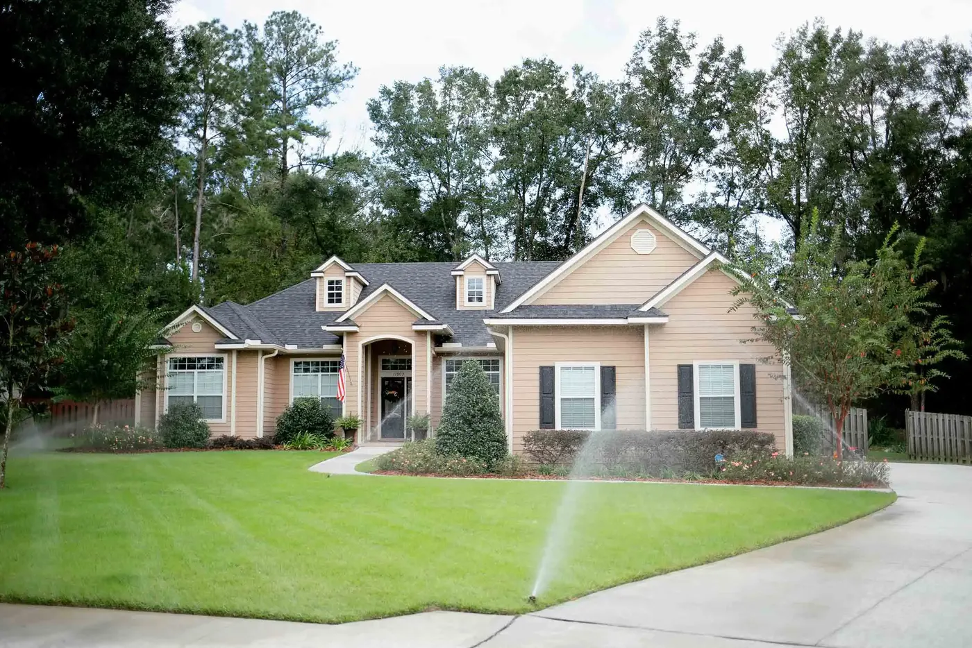 Home with sprinklers running across the front lawn
