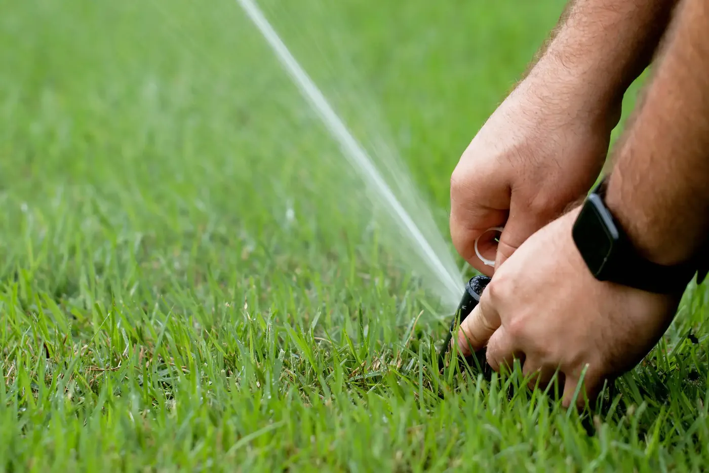 Technician adjusting a sprinkler head by hand