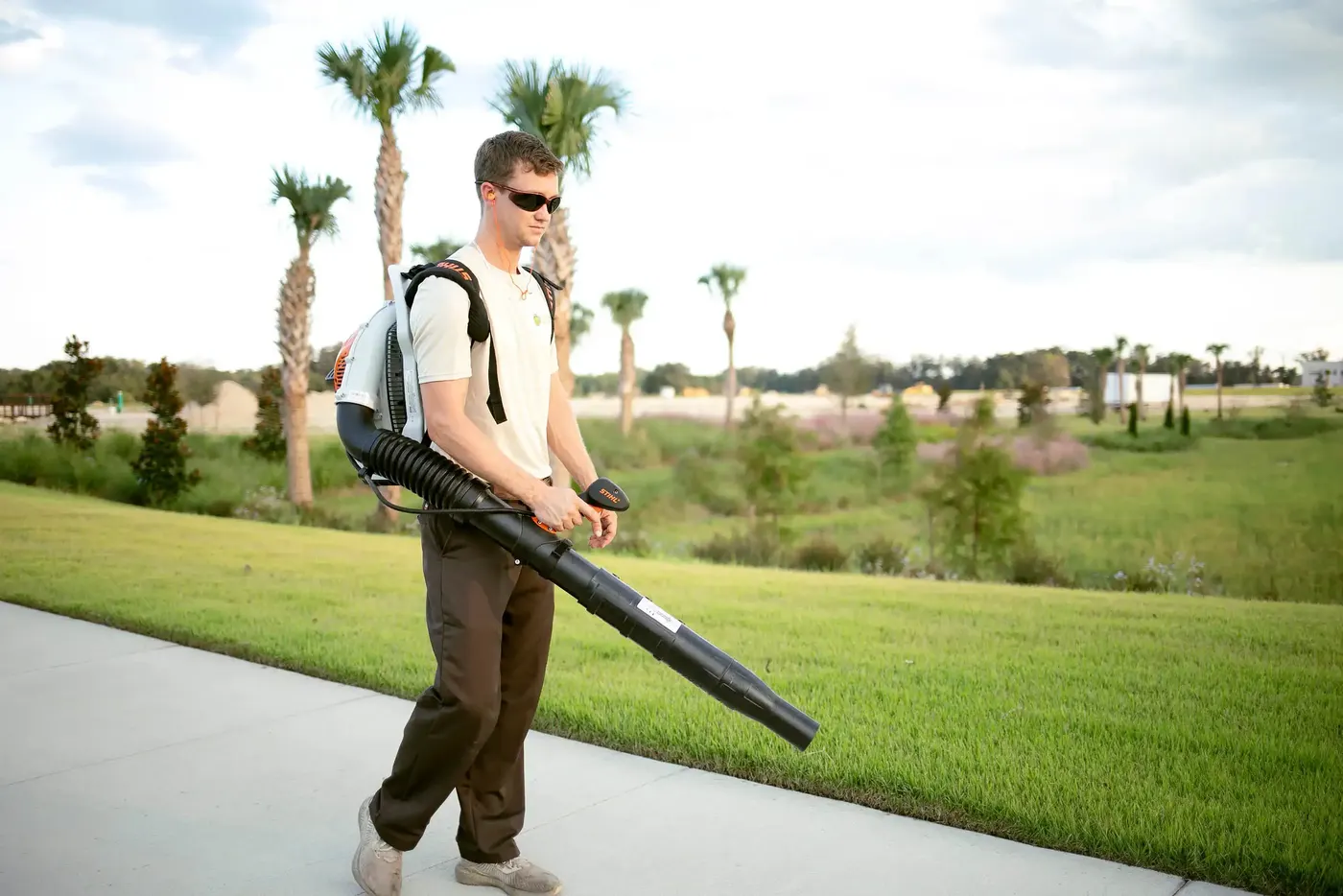Crew member clearing a path with a backpack blower