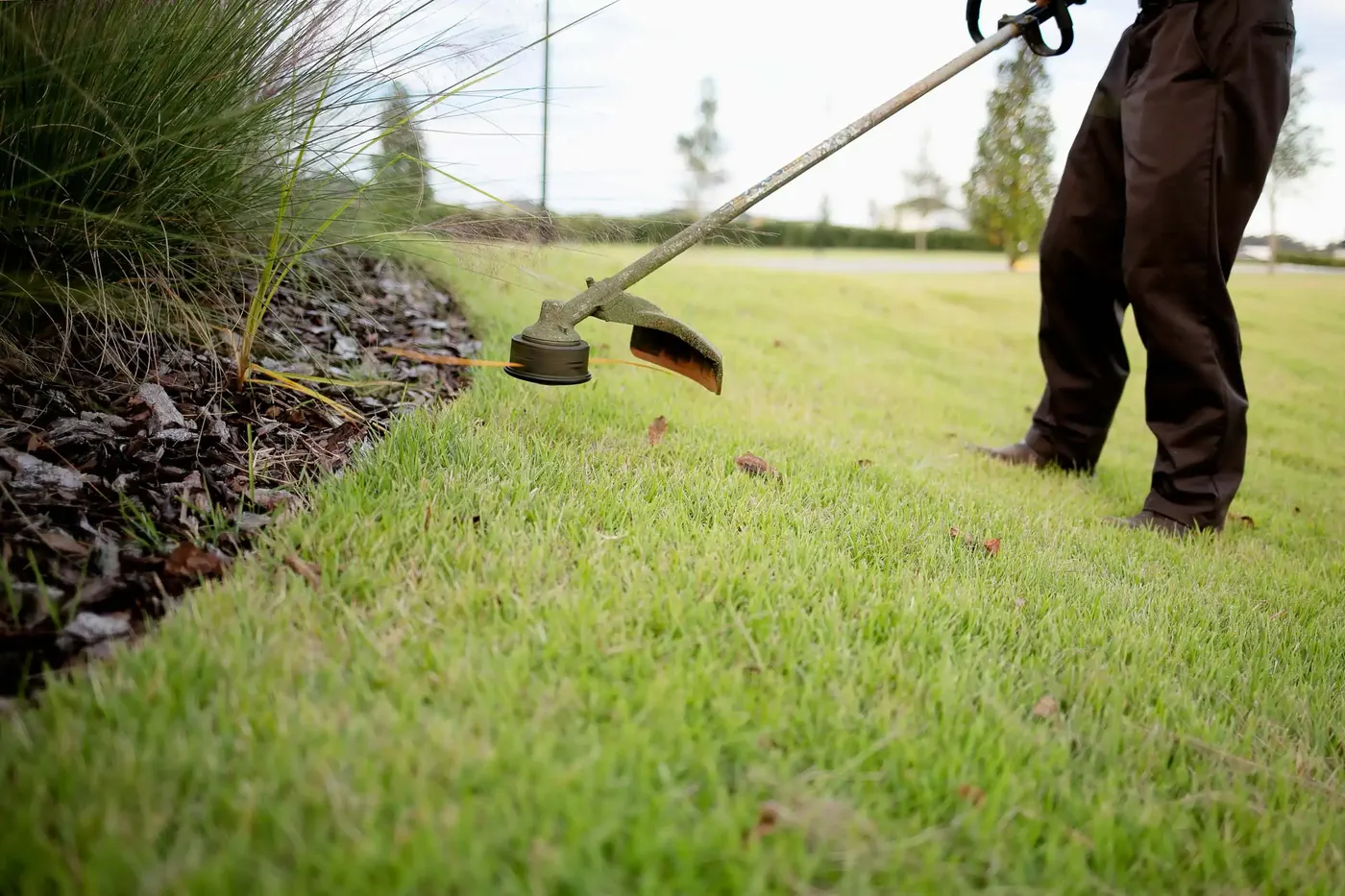 Crew member edging a lawn with a string trimmer