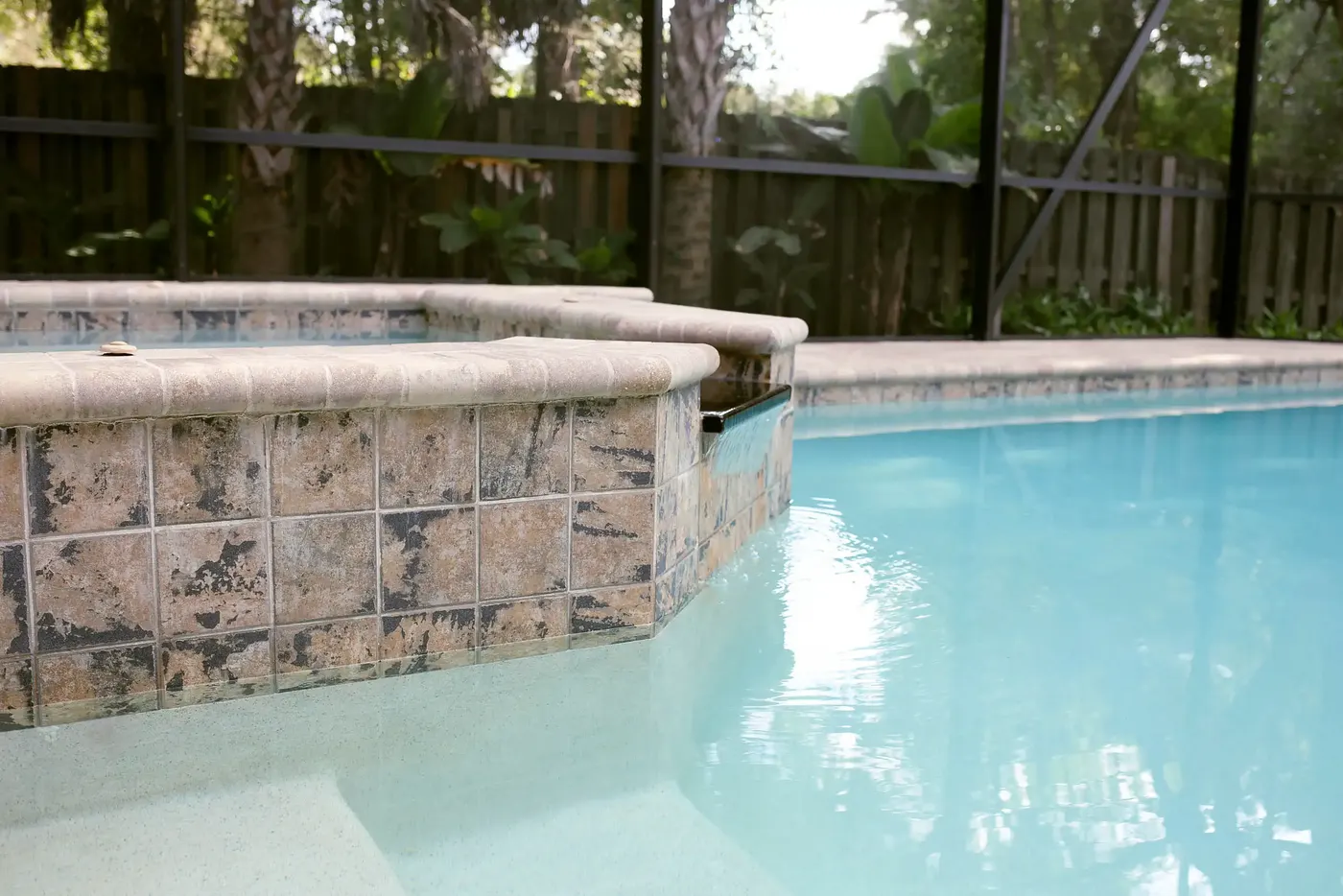 Pool and spa with stone tile inside a screened enclosure