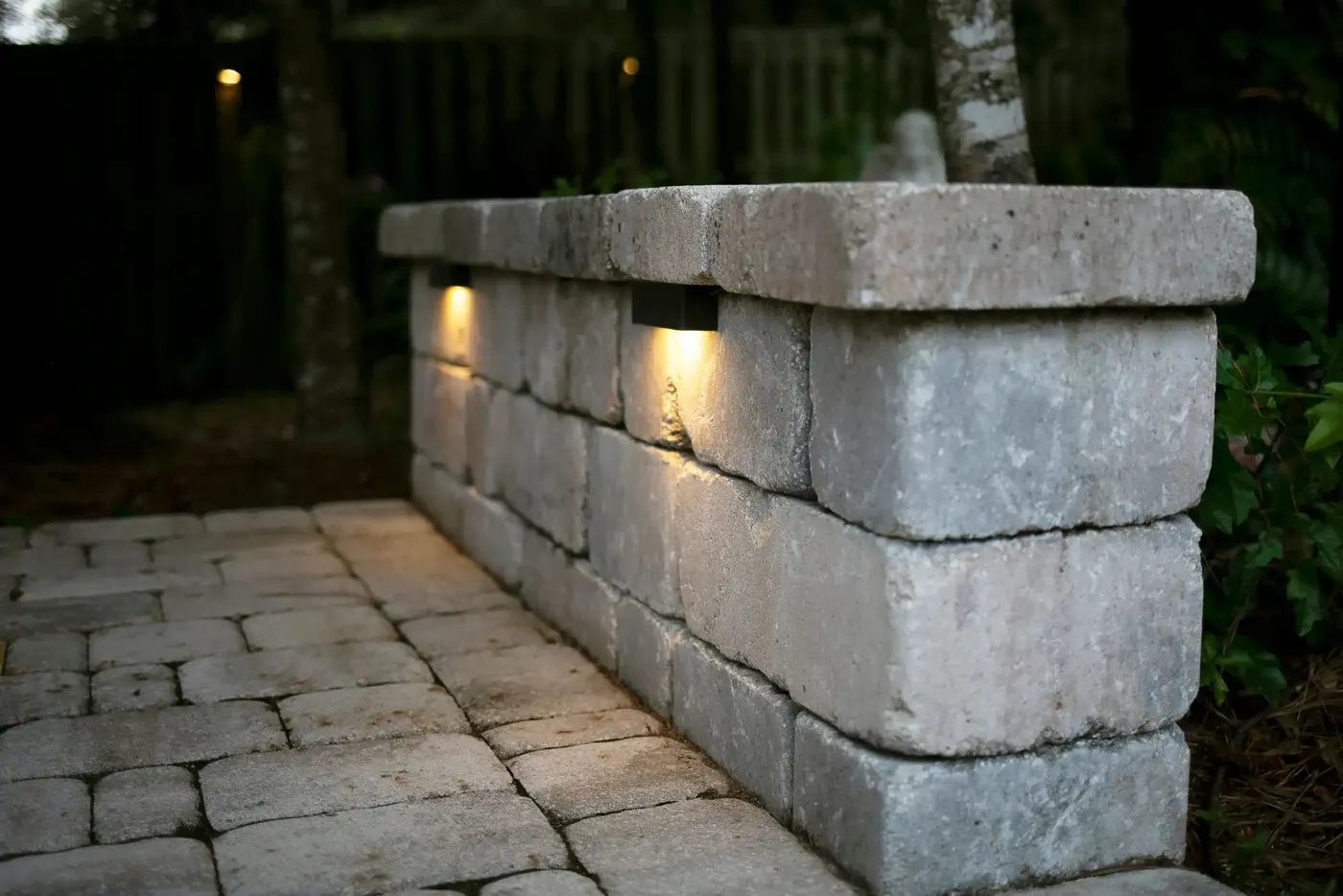 Stone seating wall with built-in lights on a paver patio at dusk